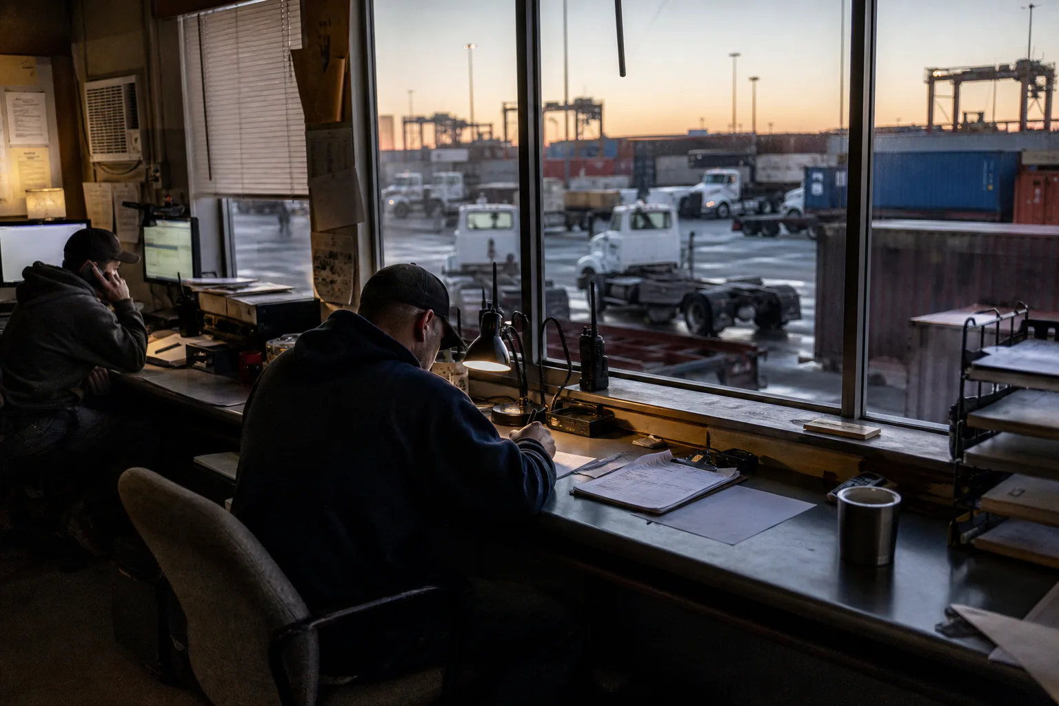 An early-shift drayage dispatch room overlooking a working container yard